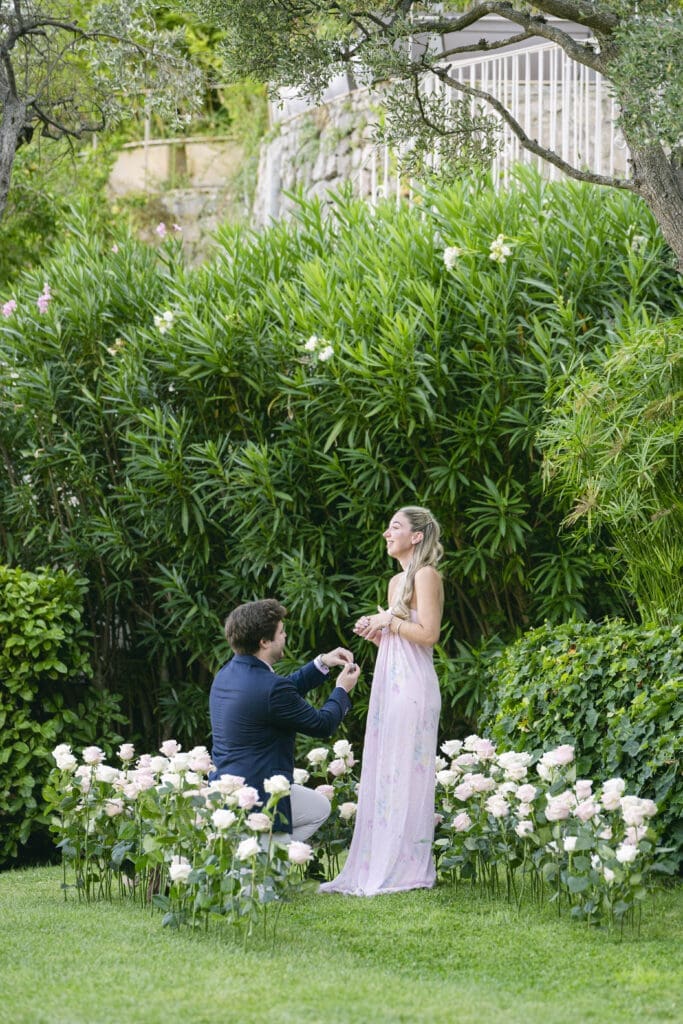 Demande en mariage genou à terre entouré de roses aux Jardins de la Chèvre d'Or
