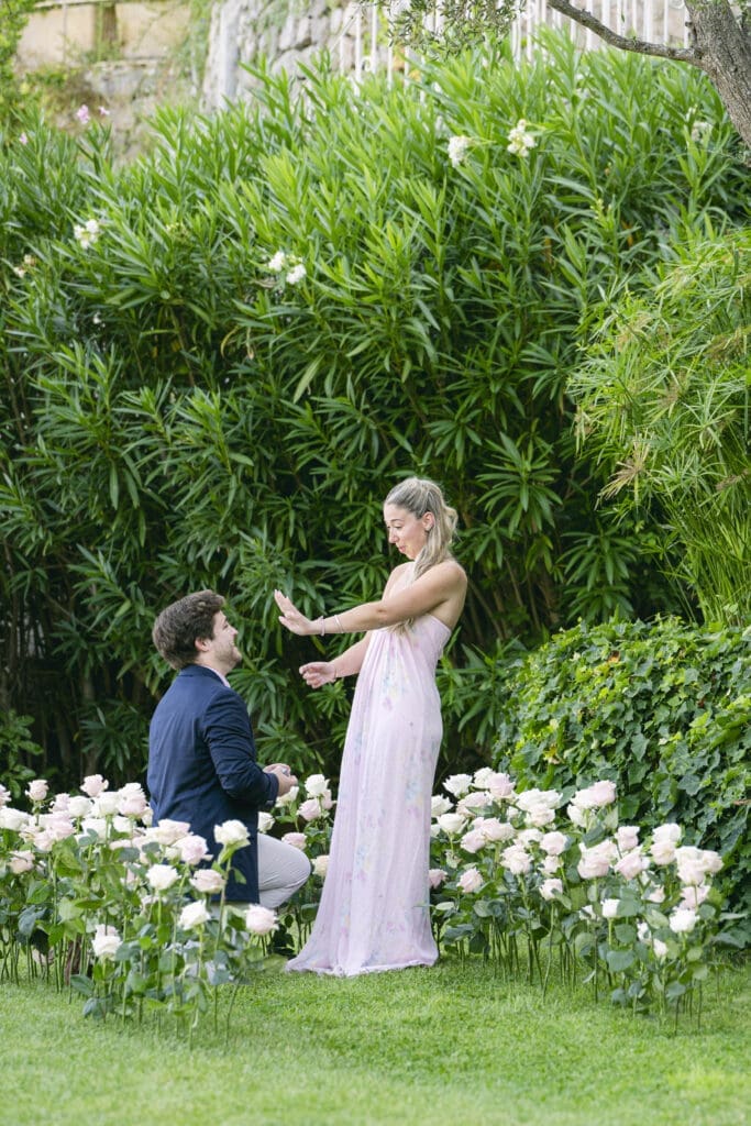 Demande en mariage genou à terre entouré de roses aux Jardins de la Chèvre d'Or